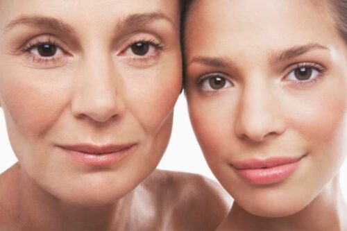 Close-up portrait of a mother and daughter, smiling, posing against each other.